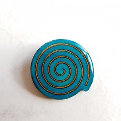 Broche artisanale en forme spirale turquoise et bronze scintillant avec léger ajourement entre les spirales encastrées.