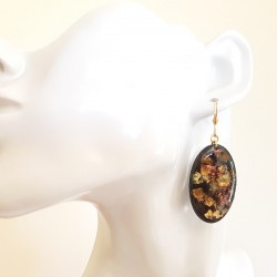 Jolie paire de boucles d'oreilles pendantes femme noir et or pailleté, elle forme ovale, aspect émail.